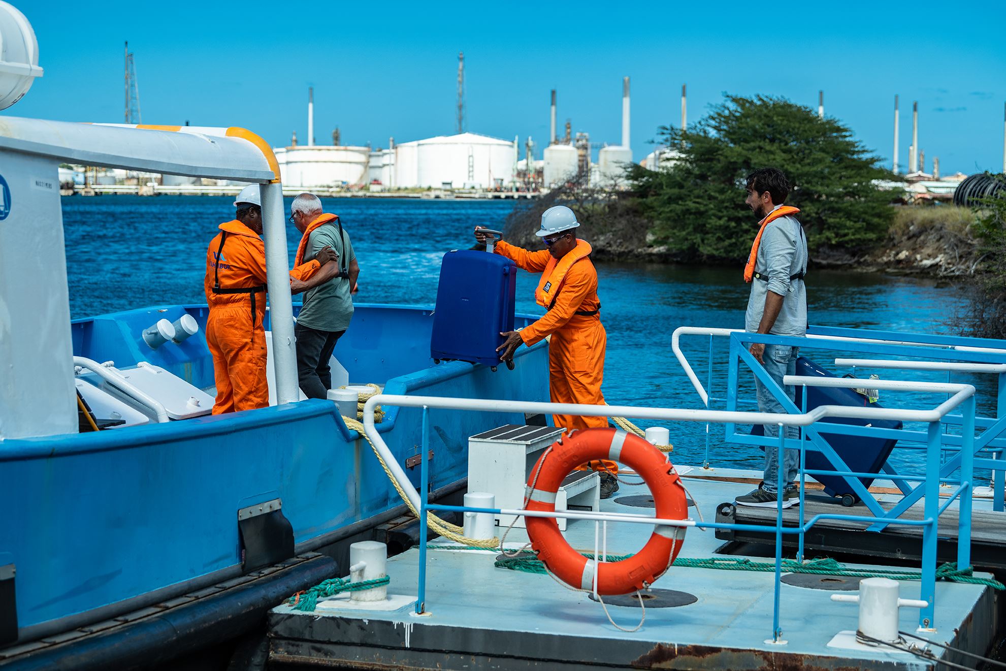Crew members and luggage being assisted between a launch and the quay